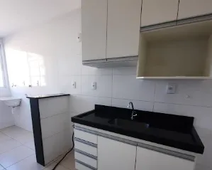 Cozinha com armários brancos e pia de granito preto no apartamento de 2 quartos