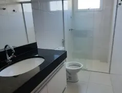 Banheiro com revestimento branco e bancada escura no apartamento de 2 quartos