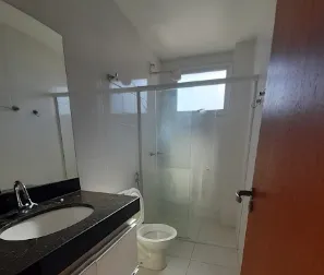 Banheiro com bancada de granito escuro e box de vidro no apartamento de 1 quarto
