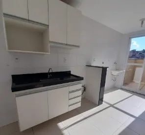 Cozinha branca com bancada escura e porta para a varanda no apartamento de 1 quarto